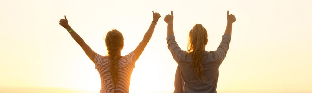 Two girls on the sunset with their thumbs up