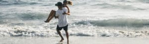 man carrying woman on seashore