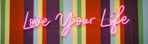 pink neon sign that reads love your life